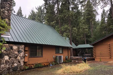 Green standing seam metal roof on a log cabin