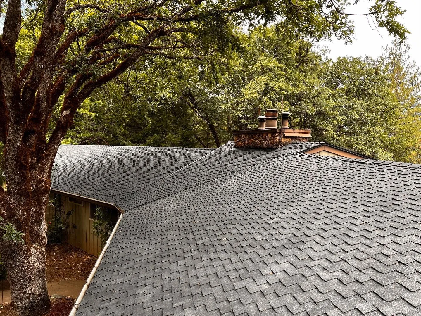 After: Charcoal shingle roof with a brick chimney